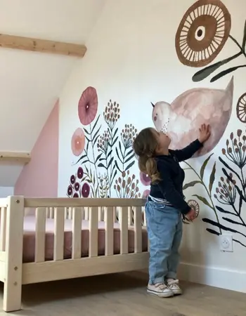 petite fille qui est contente du papier peint panoramique de sa chambre