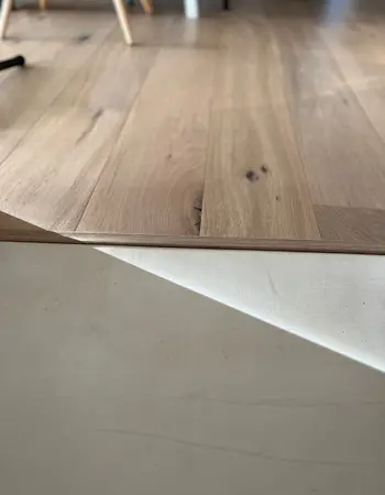 détail finition parquet d'un salon avec un autre sol en béton ciré